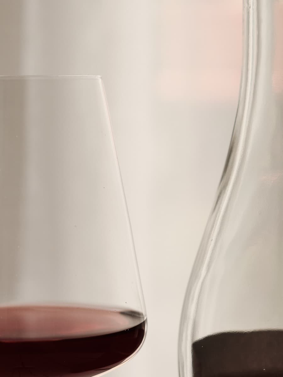 Ein Glas Rotwein neben einer Karaffe im Gegenlicht